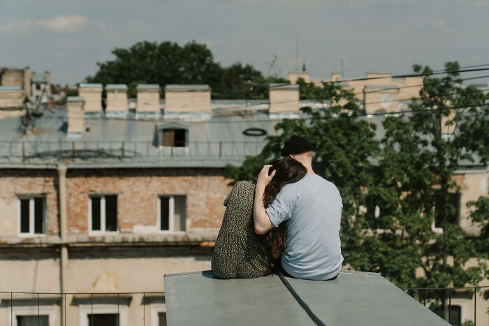 A couple sitting on a rooftop, sharing a quiet moment, represents eye-opening moments as they overlook a historic building.