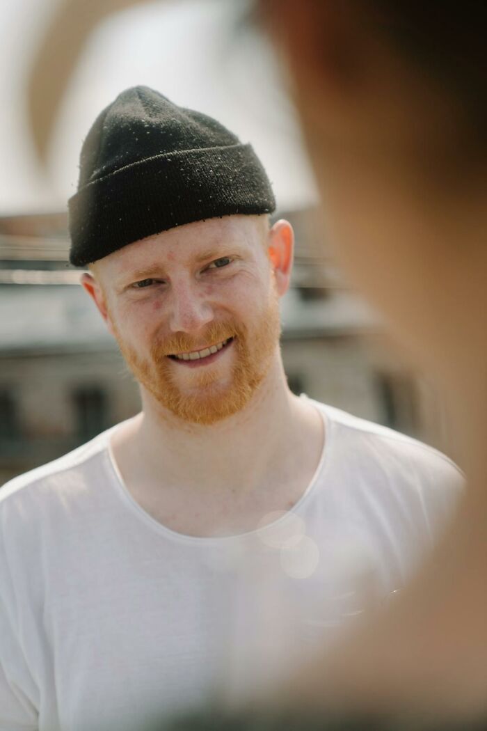 Smiling man wearing a black beanie and white shirt experiencing culture shock abroad.