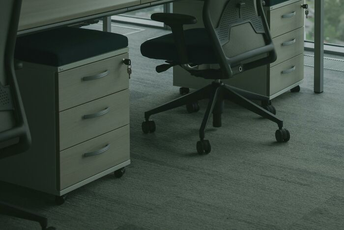 Empty office space with ergonomic office chairs and drawer units highlighting perks of not having to go to the office.