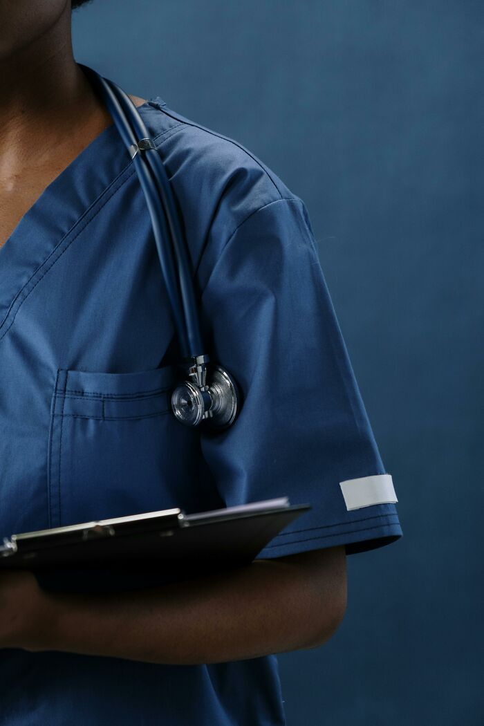 Healthcare worker in blue scrubs with stethoscope and clipboard, representing insane workplace moments in medical setting.