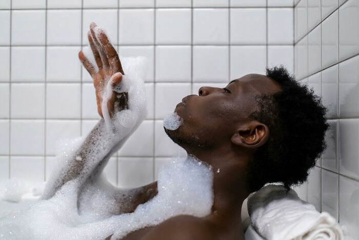 Man relaxing in a bathtub with bubbles, challenging stereotypes about "real men."