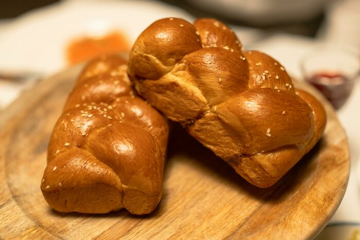 Freshly baked challah bread on a wooden board, humorous dinner context possibly overheard.