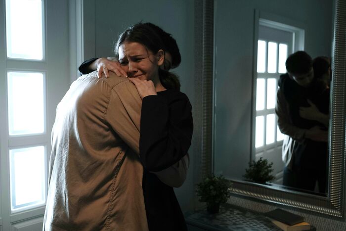 Two people embracing in a dimly lit room, conveying hardest harsh realities about life emotions.