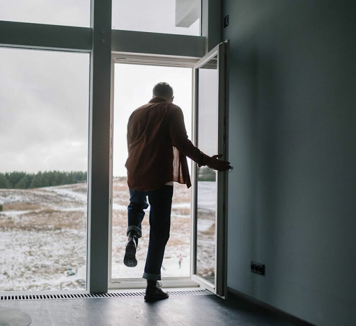 Man stepping outside through a glass door, representing a moment of personal revenge on power.