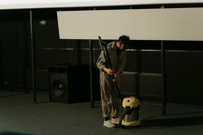 Person cleaning a theater floor with a vacuum, highlighting a profession often overlooked until needed.