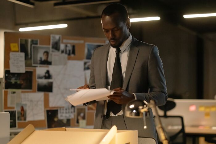 Man in suit examining documents, representing assumptions about people's jobs in an office setting.