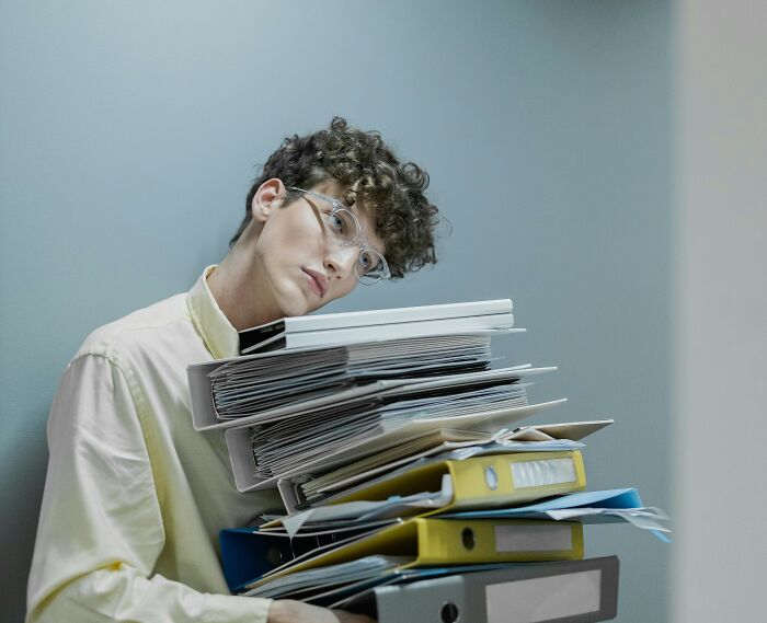 Person overwhelmed by papers, illustrating hardest harsh realities about life.