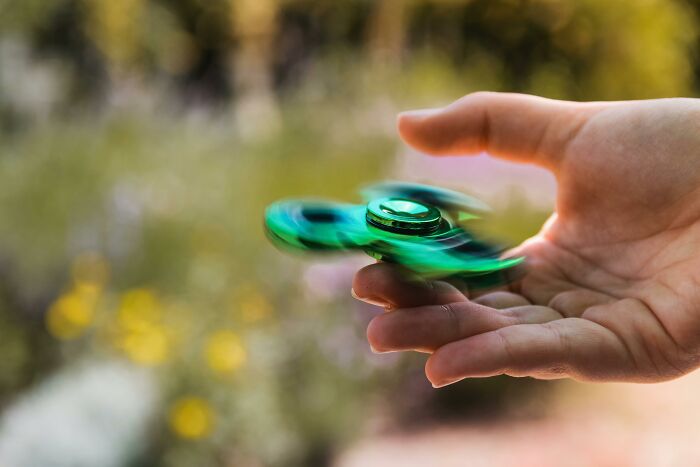 A green fidget spinner in motion on a person's hand, illustrating change mindsets with therapists' knowledge.