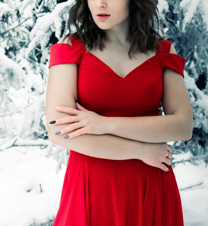 Woman in red dress standing in snowy landscape, experiencing culture shock in winter attire.