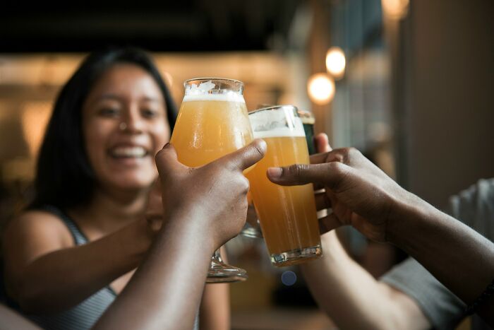 Group of friends raising glasses of beer in a toast, highlighting social moments and real men do stereotypes.