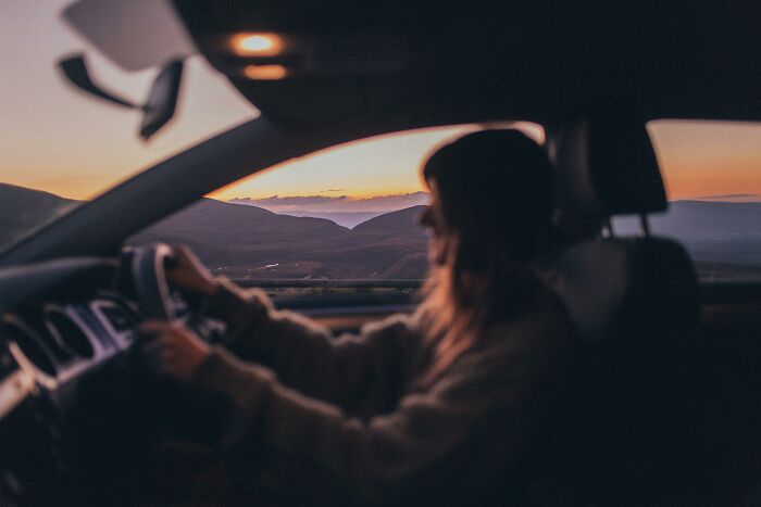A person driving a car at sunset, highlighting driving knowledge with scenic mountain views.