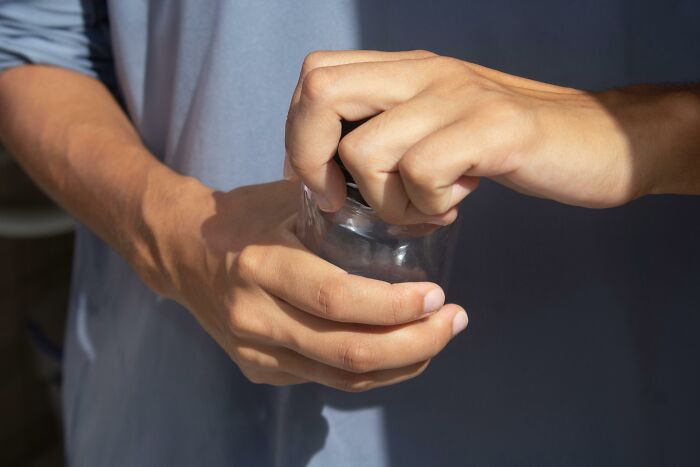 Hands opening a jar, using a brilliant-life-hack technique for an easy solution.