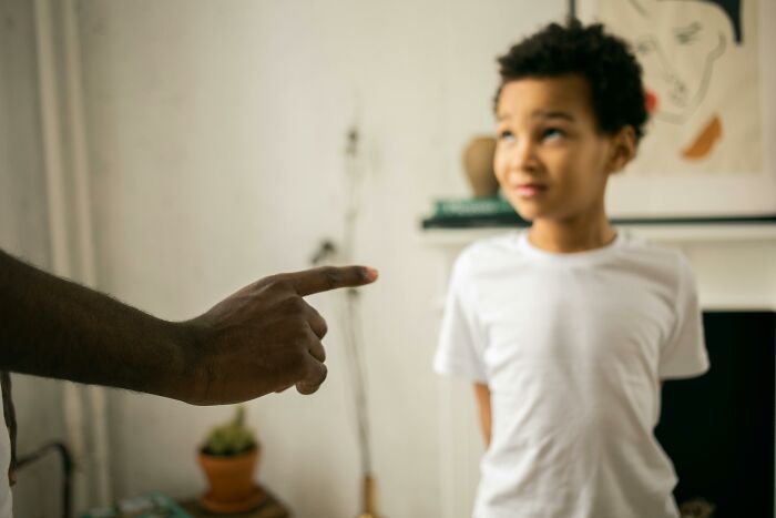 Child in white shirt looking up, while an adult's hand points. Scenario hints at hilarious overheard conversations.