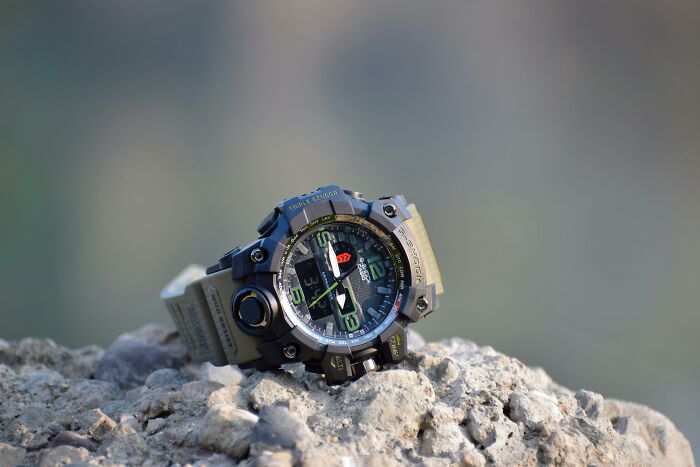 Durable watch with rugged design sitting on rocks, emphasizing longevity.