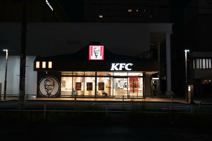 KFC restaurant at night, potential setting for hilarious overheard conversations, with bright lights and signage.