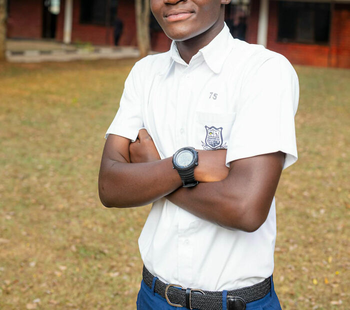 Young man in a white shirt with folded arms, standing confidently outdoors, symbolizing power and confidence.