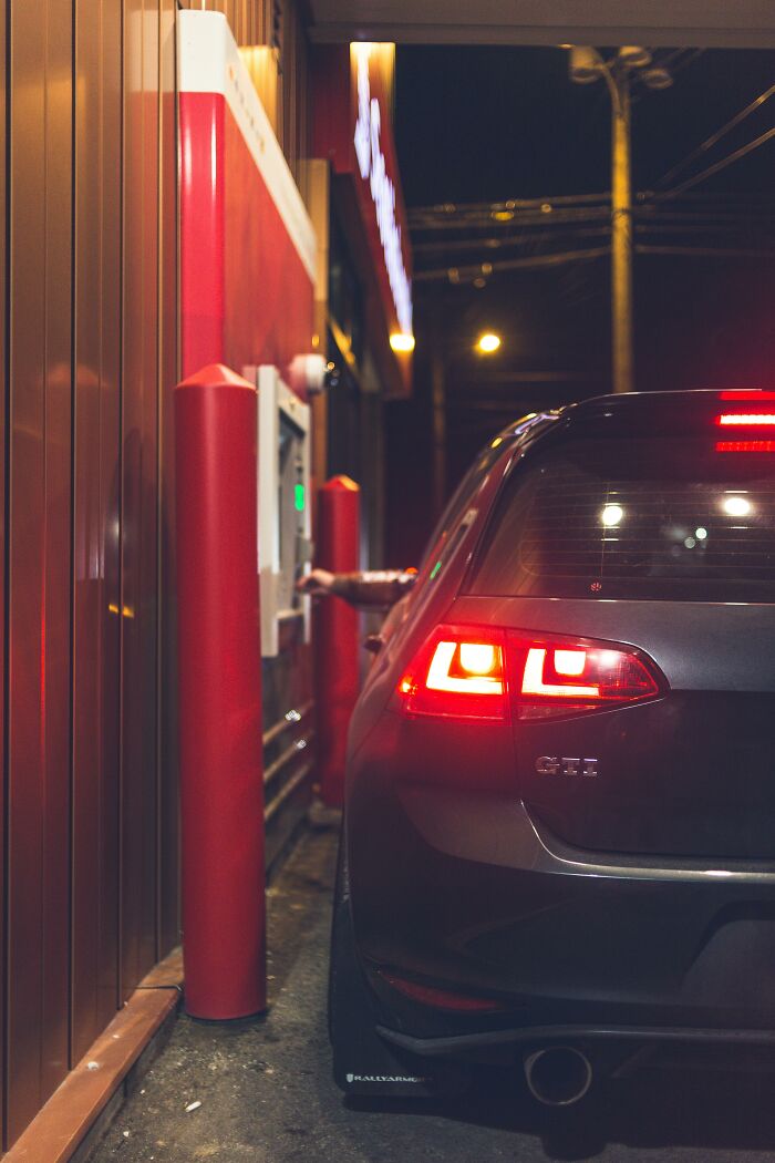 Car at a drive-thru ATM at night, capturing one of the insane workplace moments in an urban setting.