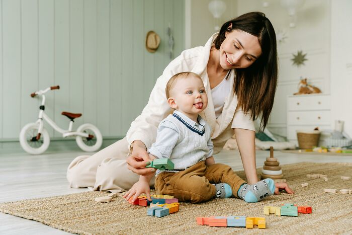 Mother and baby enjoying eye-opening moments with colorful blocks on the floor, bicycle in background.