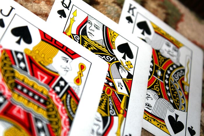 Close-up of playing cards with spade suits, featuring face cards.