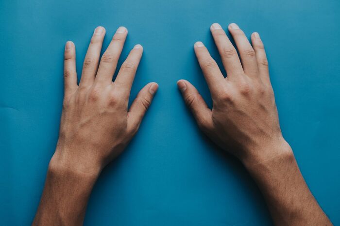 Two hands with palms down on a blue background, relating to men and judgment.