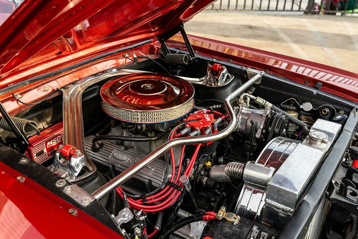 Open hood of a red car showcasing a detailed engine, a high-value good to purchase before price hikes due to tariffs.