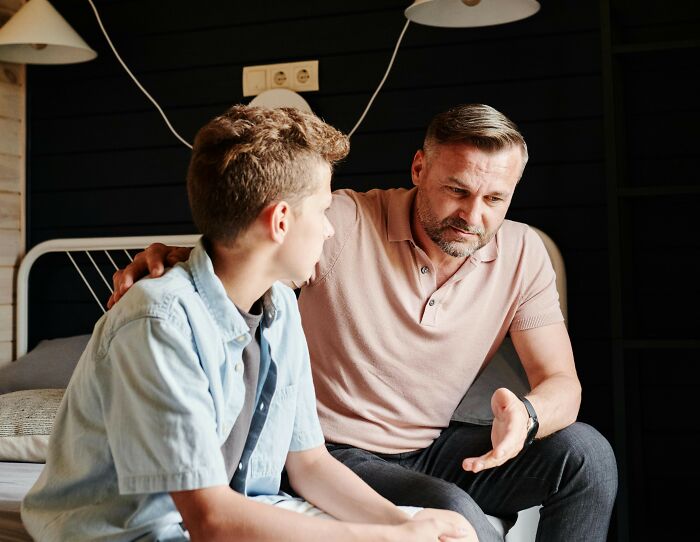 Father and son sharing an important moment, with the father speaking intently and the son listening closely.