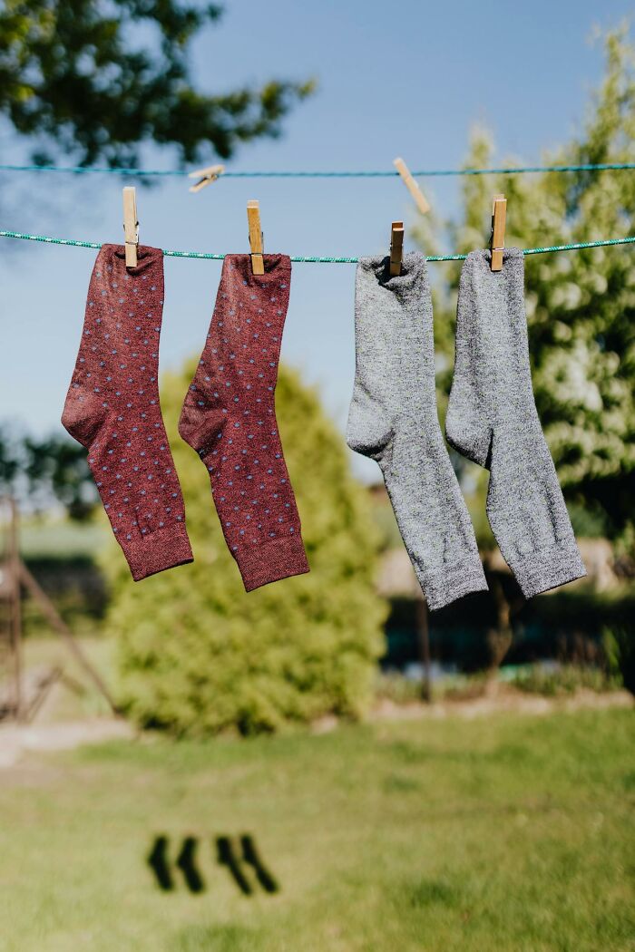 Frugal living: four socks drying on a clothesline outdoors in sunlight.