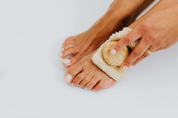 Person scrubbing feet with a pumice stone to improve hygiene habits.