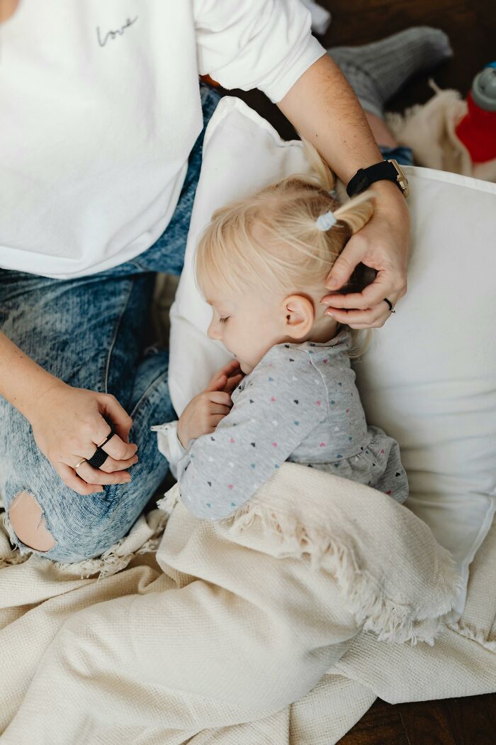Parent comforting a sleeping child at home, utilizing parenting hacks and reverse psychology strategies.