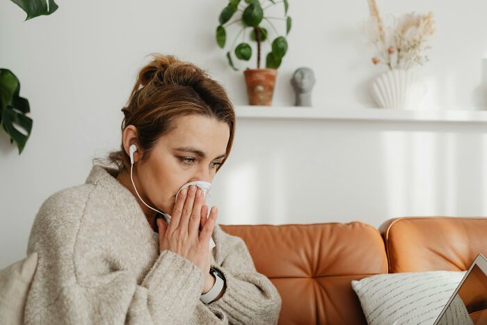 Woman on couch, using tissue while listening to music.