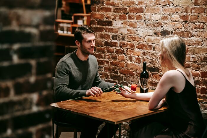 Man and woman having a meaningful conversation over dinner, evoking eye-opening moments in a cozy restaurant setting.