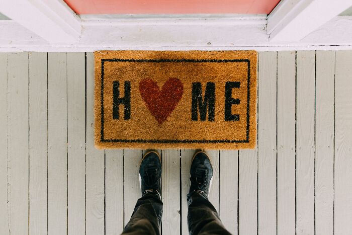 Person standing at a doormat with a red heart, symbolizing home, representing change in mindsets.