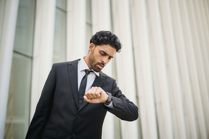 A man in a suit looking at his watch, illustrating common work skills people lack in time management.