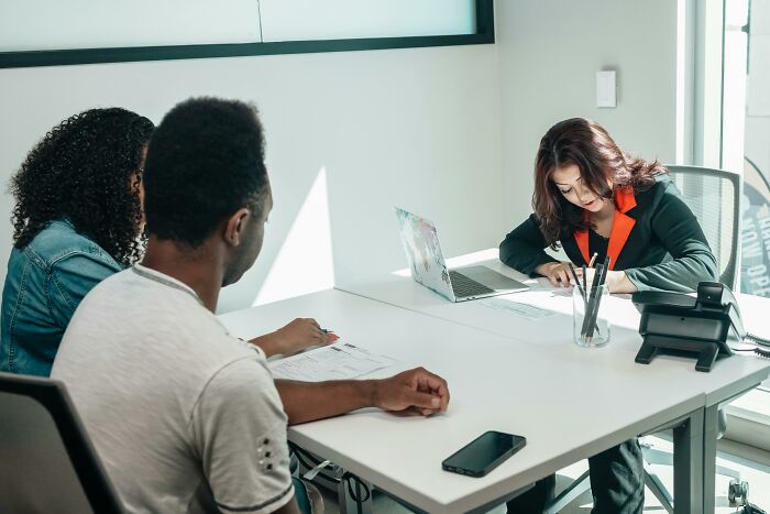 Pair discussing traumatizing experiences with a woman writing notes in an office.