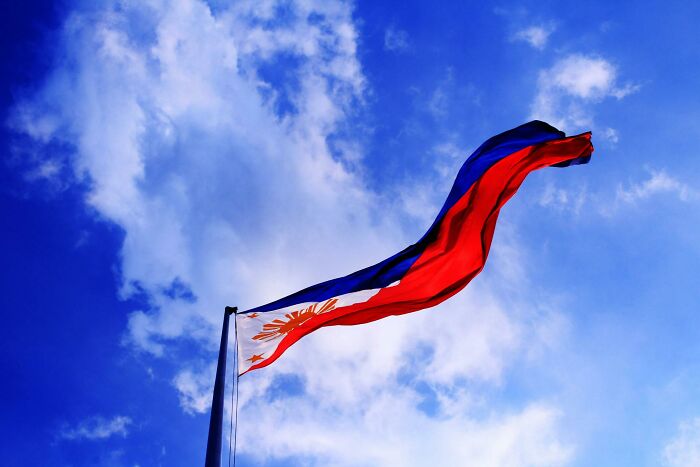 Philippine flag waving against a blue sky, representing shocking cultural differences.
