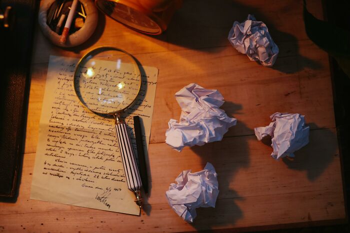 Magnifying glass and crumpled papers on a desk, suggesting a detective scene related to famous characters.