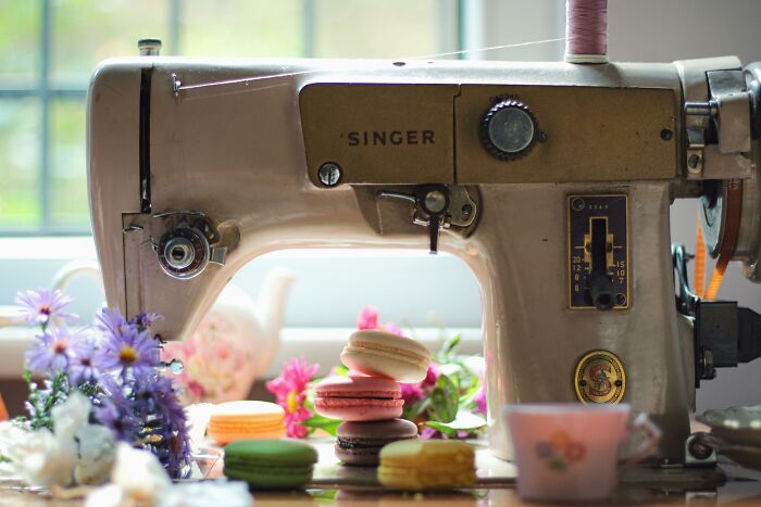 Vintage Singer sewing machine, showcasing durable design, surrounded by colorful macarons and flowers.