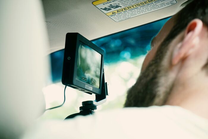 A man in a car using a camera monitor, illustrating Self-Paying-Products technology in action.