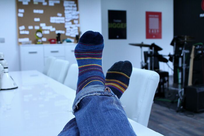 Person wearing colorful striped socks with feet up on office chair, illustrating perks of not having to go to the office