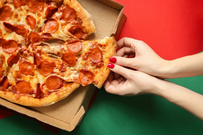 Hands grabbing a slice of pepperoni pizza from a box, representing a lighthearted moment like hilarious overheard conversations.