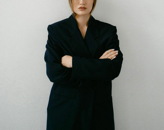 A person in a dark suit with crossed arms, conveying authority and power.