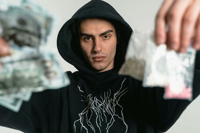 Person in a black hoodie holding blurred objects, representing rumors being spread about themselves.