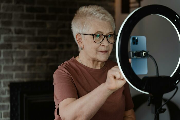 Elderly woman engaging in a video call using a smartphone and ring light, symbolizing 2025-Trends in digital communication.