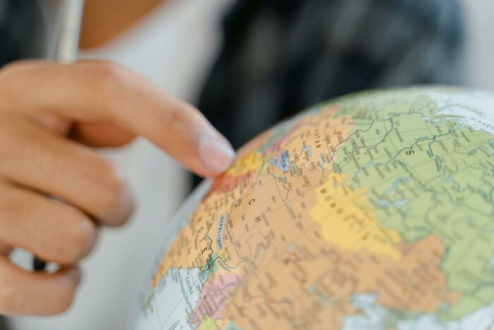 Finger pointing at a globe, possibly illustrating hilarious overheard conversations about geography.