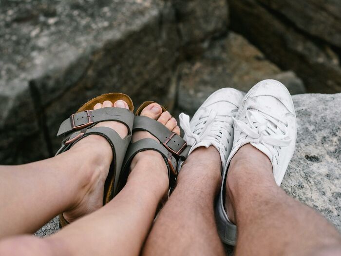 Feet wearing durable sandals and sneakers on a rocky surface, showcasing beautifully designed footwear for longevity.