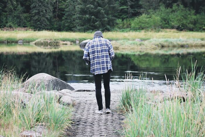 Person in plaid shirt standing near a lake in nature, representing solitude and reflection, related to 2025-Trends.