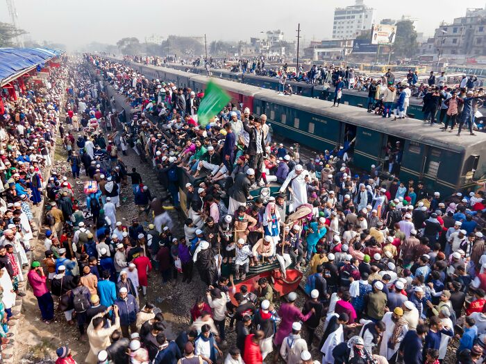 Crowded train station bustling with people on train roofs, showcasing shocking cultural differences in transportation habits.