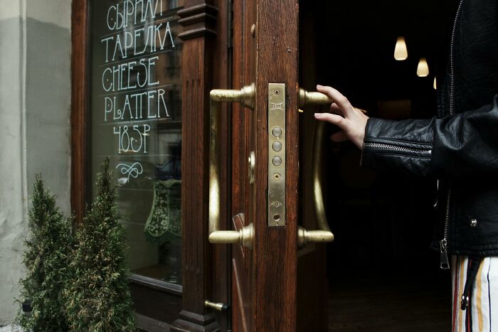 Hand opening a door with a sign listing cheese platter, highlighting common social rules people ignore.