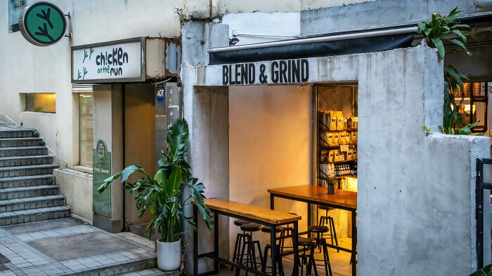 Cozy urban café with outdoor seating, featuring "Blend & Grind" signage in a city setting.