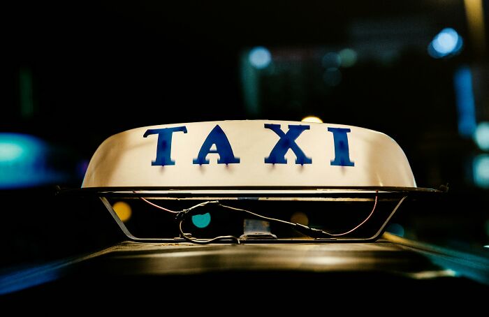 Taxi sign illuminated at night, highlighting cultural differences in transportation methods.